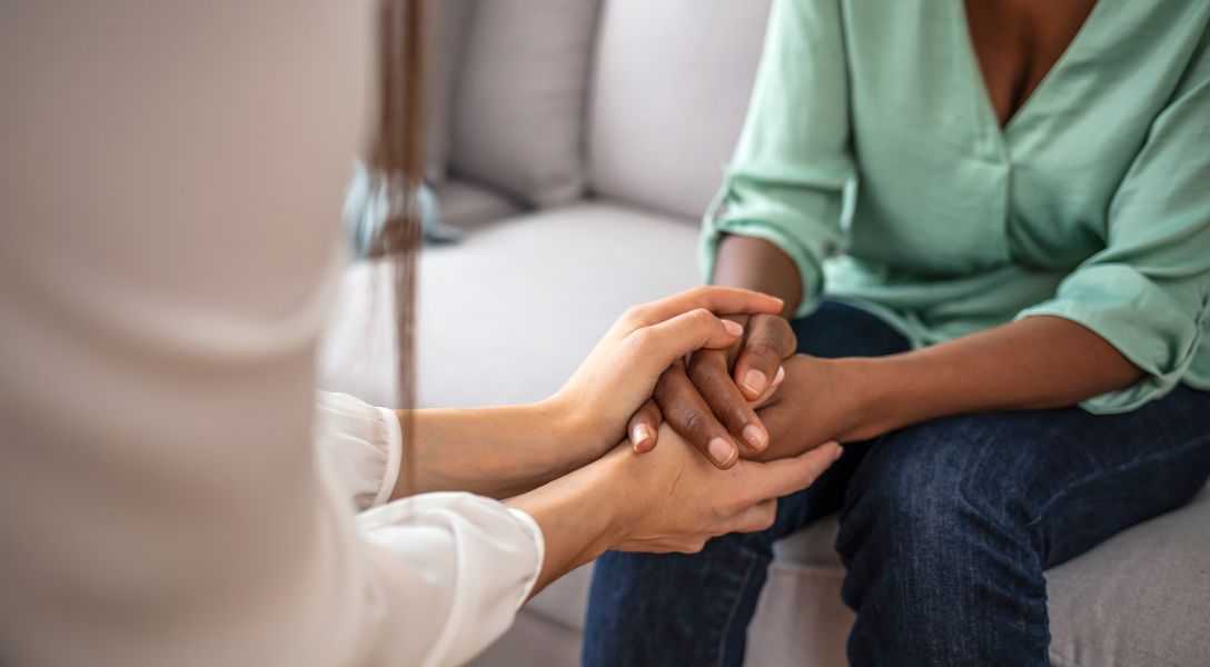 GettyImages-1334410357 A person holding their hands with another person.
