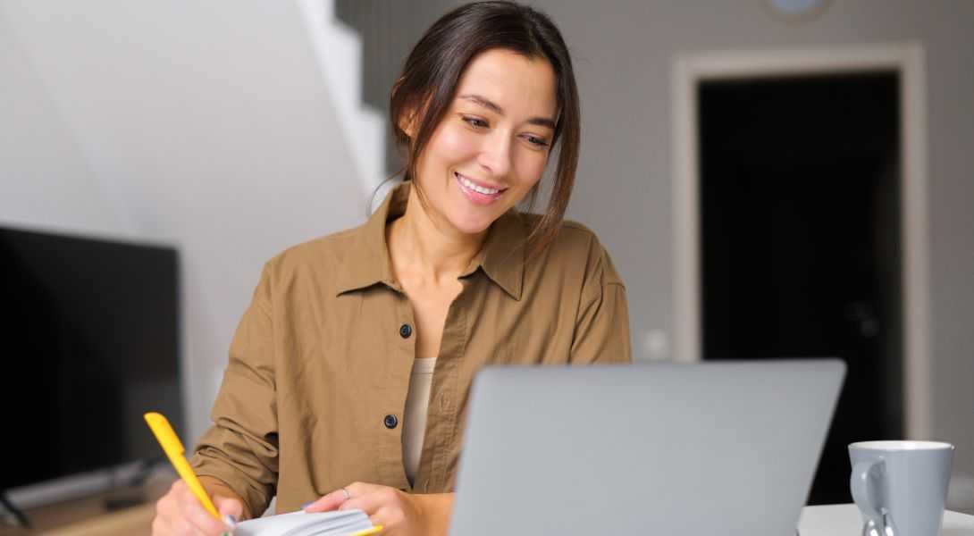 GettyImages-1365001960 A woman is smiling while looking at her laptop.