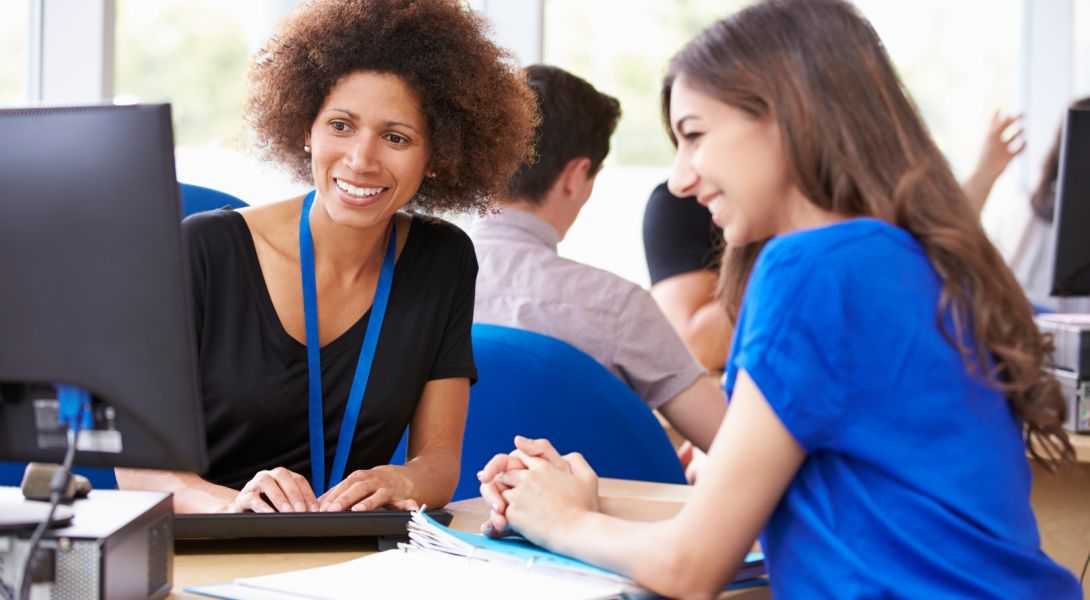 GettyImages-511793899 Two women sitting at a table with papers and laptops.