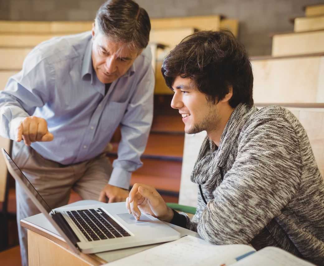 GettyImages-660651906 Two men are looking at a laptop and smiling.